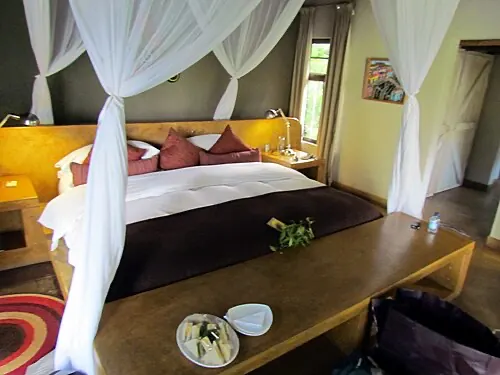 A safari suite with a draped four-poster bed and soft morning light